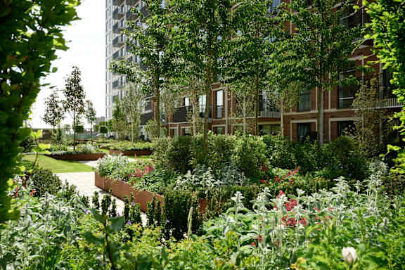 A modern apartment complex with a landscaped garden in front.