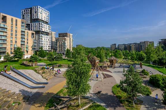 A playground in a park with a slide and a climbing frame.
