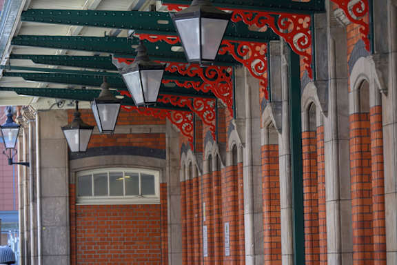 A row of red brick pillars with white trim and a row of hanging lights.