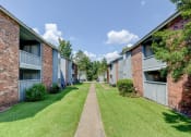 Thumbnail 7 of 8 - Sidewalk with buildings on either side at Landmark Apartment Homes, Meridian, Mississippi