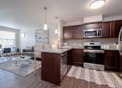 Thumbnail 3 of 9 - Kitchen area of an apartment fitted with a kitchen island, seating, stainless steel appliances, and spacious cabinets.