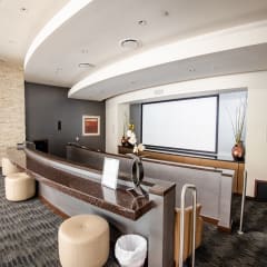 a reception area with a large screen tv on the wall and a long counter with stools