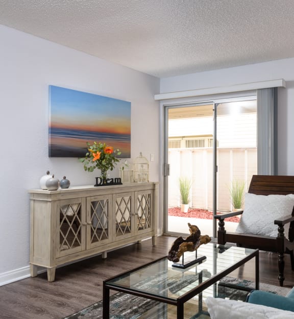 a living room with a blue couch and a glass coffee table in front of a sliding glass