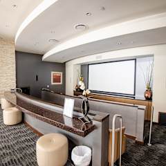 a reception area with a large screen tv on the wall and a long counter with stools