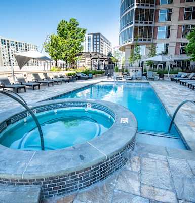 a swimming pool with a hot tub and chaise lounge chairs in front of a building