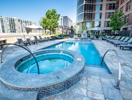 a swimming pool with a hot tub and chaise lounge chairs in front of a building