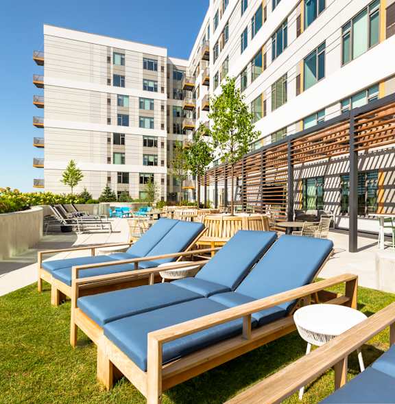 A patio with a white couch, a wicker chair, and a flat screen TV.