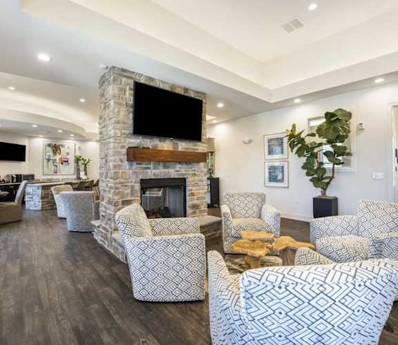 A living room with a stone fireplace and patterned chairs at The Maddox Apartments, Centerton, AR, 72719