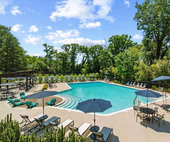 a swimming pool with umbrellas and chairs around it at Padonia Village Apartments, Timonium, 21093