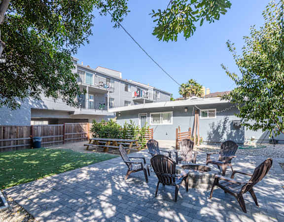 A patio with a table and chairs is surrounded by a fence and trees.