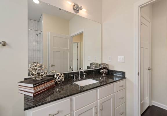 A bathroom with a black granite countertop and white cabinets.