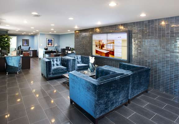 a lobby with blue couches and a large screen on the wall at Versailles on the Lakes Oakbrook*, Oakbrook Terrace, 60181