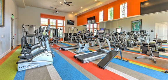 a gym with treadmills and other exercise equipment and windows