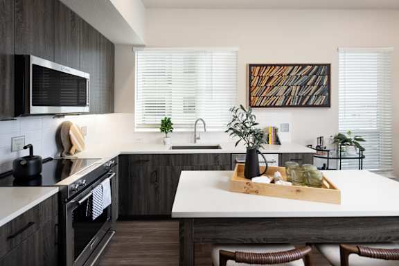 A modern kitchen with dark wood cabinets and white countertops.