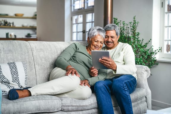 an older couple sitting on a couch looking at a tablet at The Legends of Blaine 55+, Blaine, MN 55449