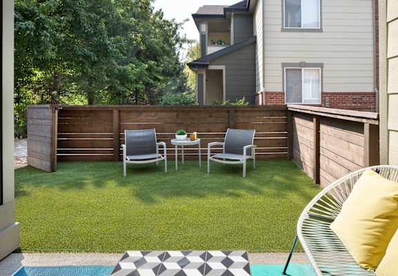 A backyard with a lawn, chairs, and a bench.