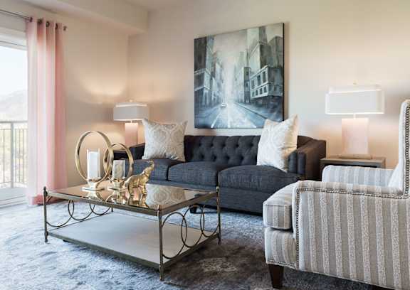 A living room with a black couch, a coffee table, and two lamps.