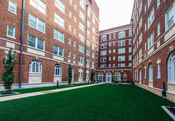 a courtyard between two brick buildings with a green lawn at Residences at Forest Park, Saint Louis, MO