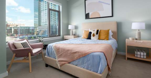 A bedroom with a large bed and a chair by the window.