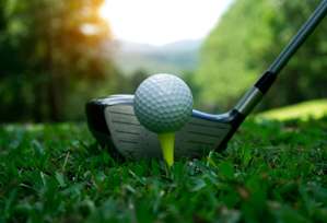 A golf ball is on a tee next to a golf club.