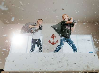 two kids playing on a bed in the snow