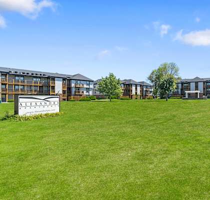 a grassy area with apartment buildings in the background