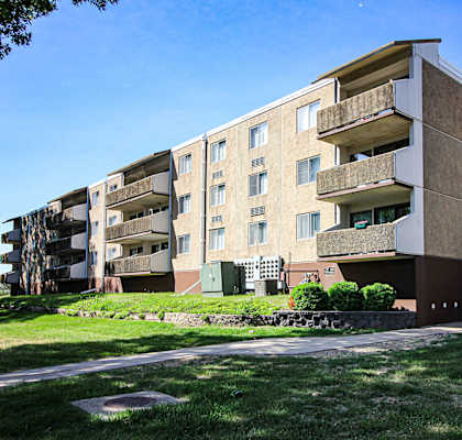an apartment building on a sunny day with a sidewalk