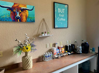 a counter with a vase of flowers on it and a painting of a cow on the