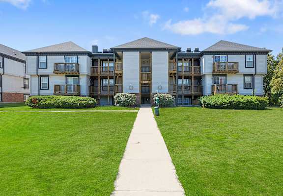 a large apartment building with balconies and a grassy area in front of it