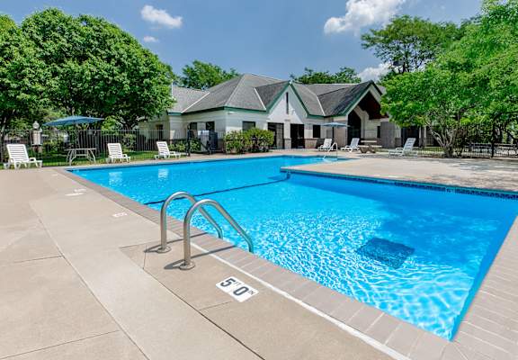 A swimming pool with a ladder and a house in the background.