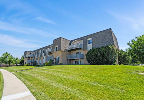 a building with a green lawn and a sidewalk in front of it