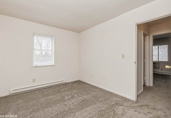 an empty room with carpet and a door to a bathroom