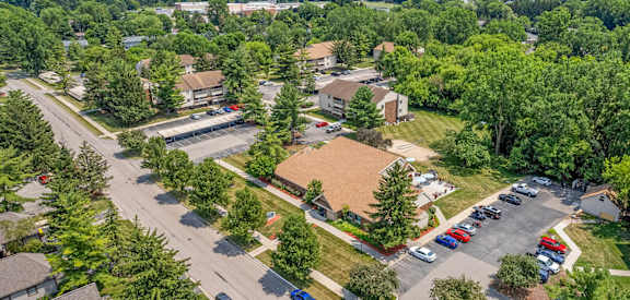 A bird's eye view of a residential area with houses, cars, and trees.