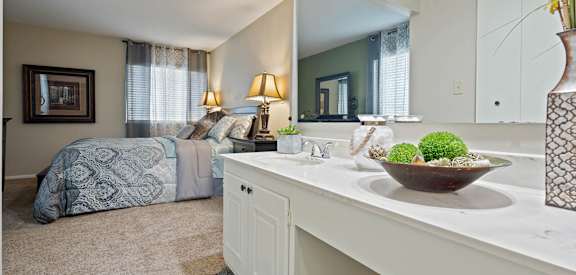 a bathroom with a sink and a bedroom with a bed