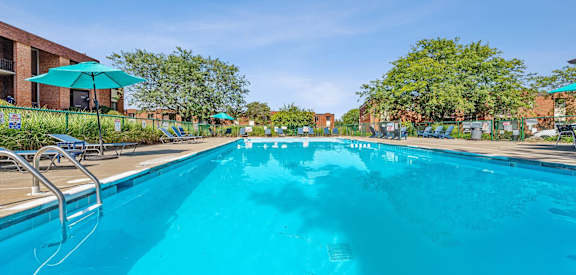 a large swimming pool with chairs at an apartment complex