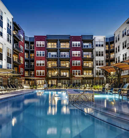 A large outdoor swimming pool surrounded by lounge chairs and umbrellas.
