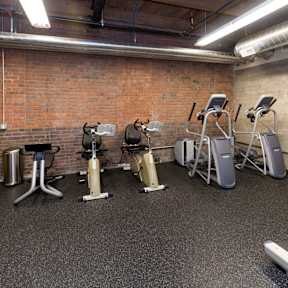 A gym with a brick wall and a variety of exercise equipment.at Riverpoint Lofts, Iowa, 50309