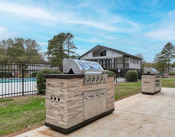 the backyard has an outdoor grill and a pool with a house in the background