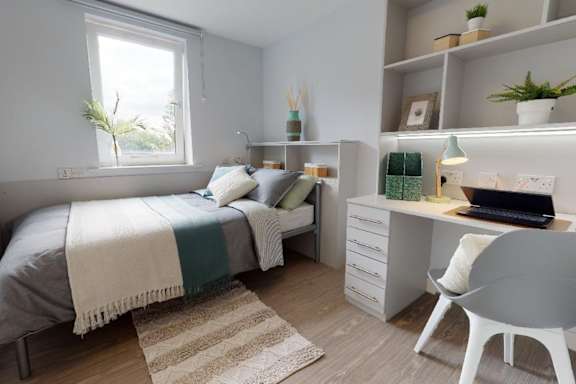 A bedroom with a bed, desk, and chair.
