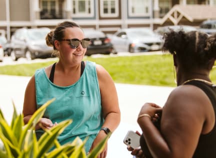 two women talking to each other in front of a plant  at Waterside Residences on Quivira, Lenexa, Kansas
