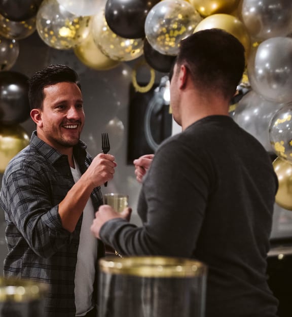 two men chatting at a party with black and gold balloons  at The Grand, Kansas City, Missouri