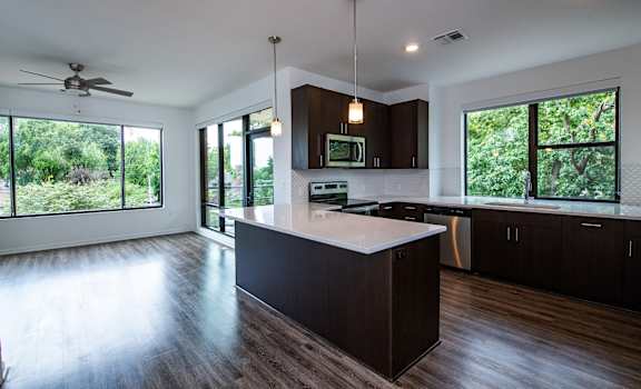 A modern kitchen with dark wood floors and a large island.