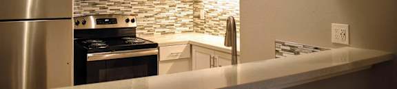 Kitchen with stainless appliances, white cabinets, and tiled backsplash