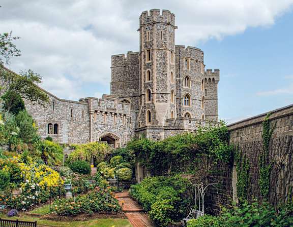 A large castle with a garden in front.