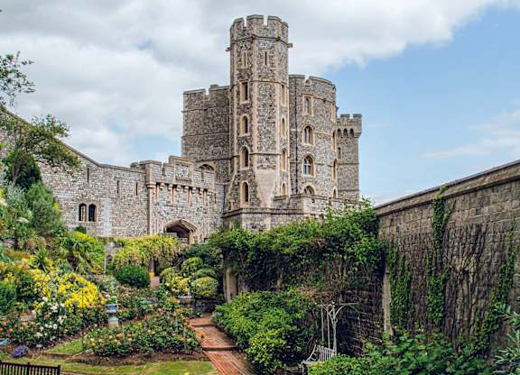 A large castle with a garden in front.