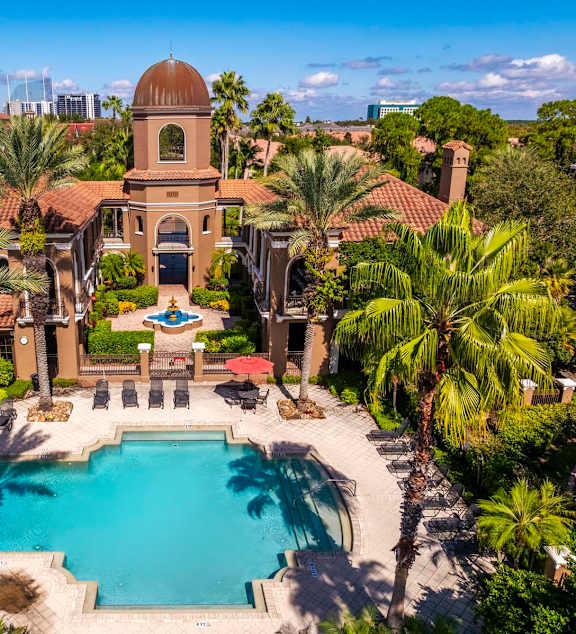 Aerial of courtyard and pool framed by palm trees and lounge seating