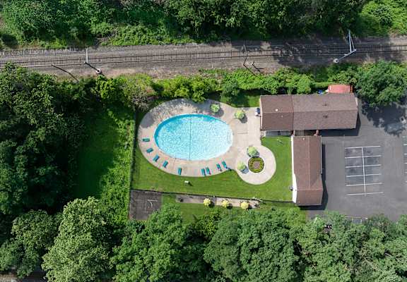 An aerial view of a swimming pool surrounded by trees and a building.