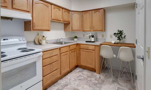 A kitchen with wooden cabinets and a white stove.