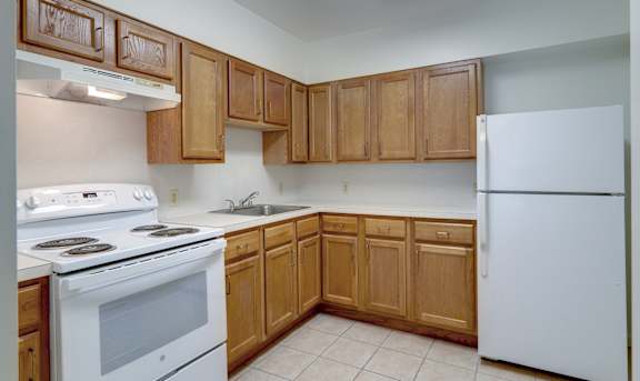 A kitchen with white appliances and wooden cabinets at The Birches at Saugerties Apartments, Saugerties, NY, 12477