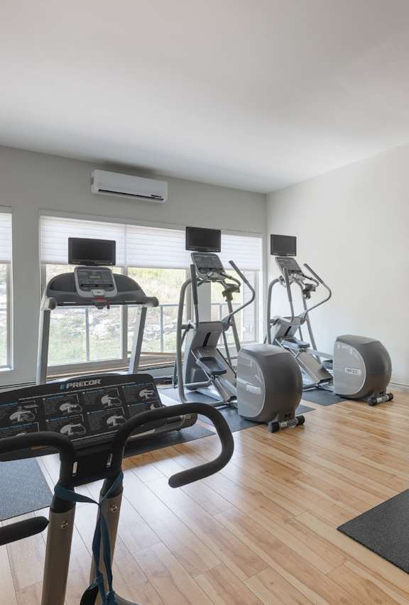 A gym with a treadmill, elliptical machines, and other exercise equipment.